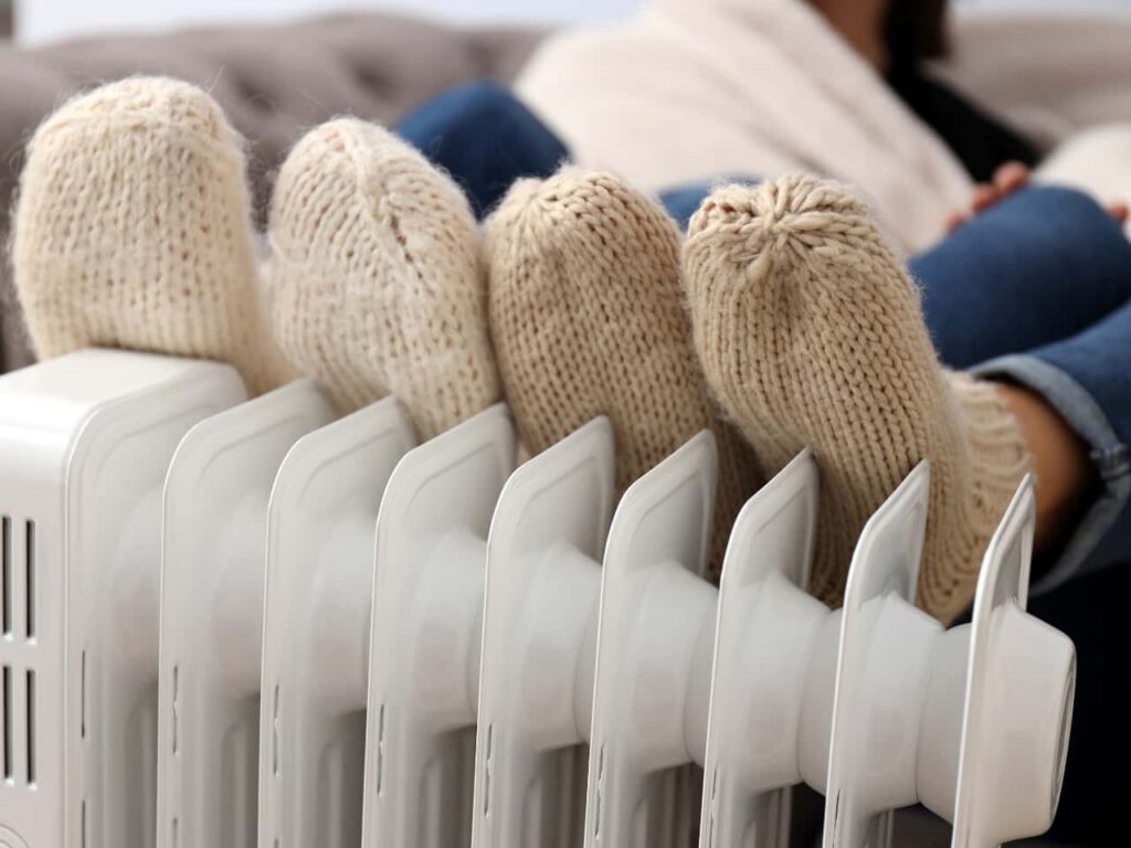 Zwei Paar Füße wärmen werden an einer Heizung gewärmt
