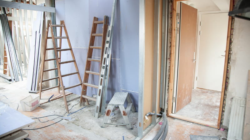 Zimmer im Umbau, bei der Renovierung, unverputzte Wände, viele Leitern und Geräte